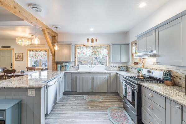Enjoy cooking in this well-equipped kitchen with a central island, oven, and large window offering a view of the outdoors.