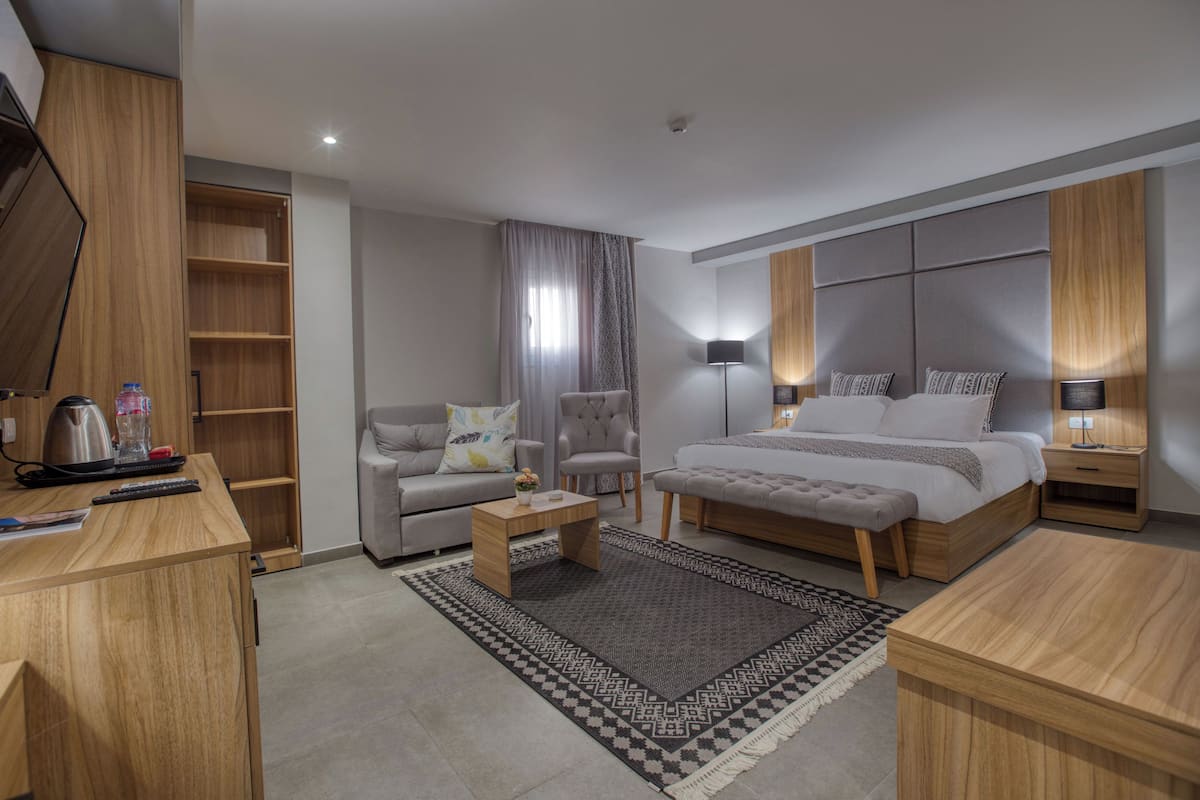 Et moderne hotelværelse med en stor seng, en sofa, et skrivebord og et garderobeskab.