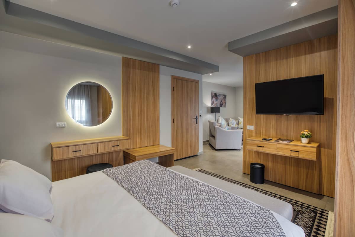 Et moderne hotelværelse med seng, skrivebord, stol, fjernsyn og garderobeskab.