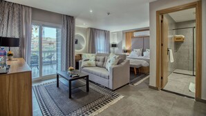 A modern hotel room with a sofa, a small table, a glass shower enclosure, and a balcony with a view of buildings. - Locanda Museum Hotel (Giza)