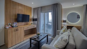 A modern living room with a flat-screen TV, wooden cabinets, a sofa, a coffee table, and a balcony with patterned curtains. - Locanda Museum Hotel (Giza)