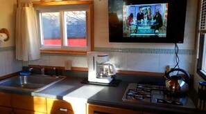 Enjoy a functional kitchen with a sink, coffee maker, and TV for a convenient stay.