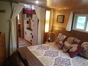 Relax in this inviting bedroom with a large bed, comfortable chair, and a stylish table with a lamp.