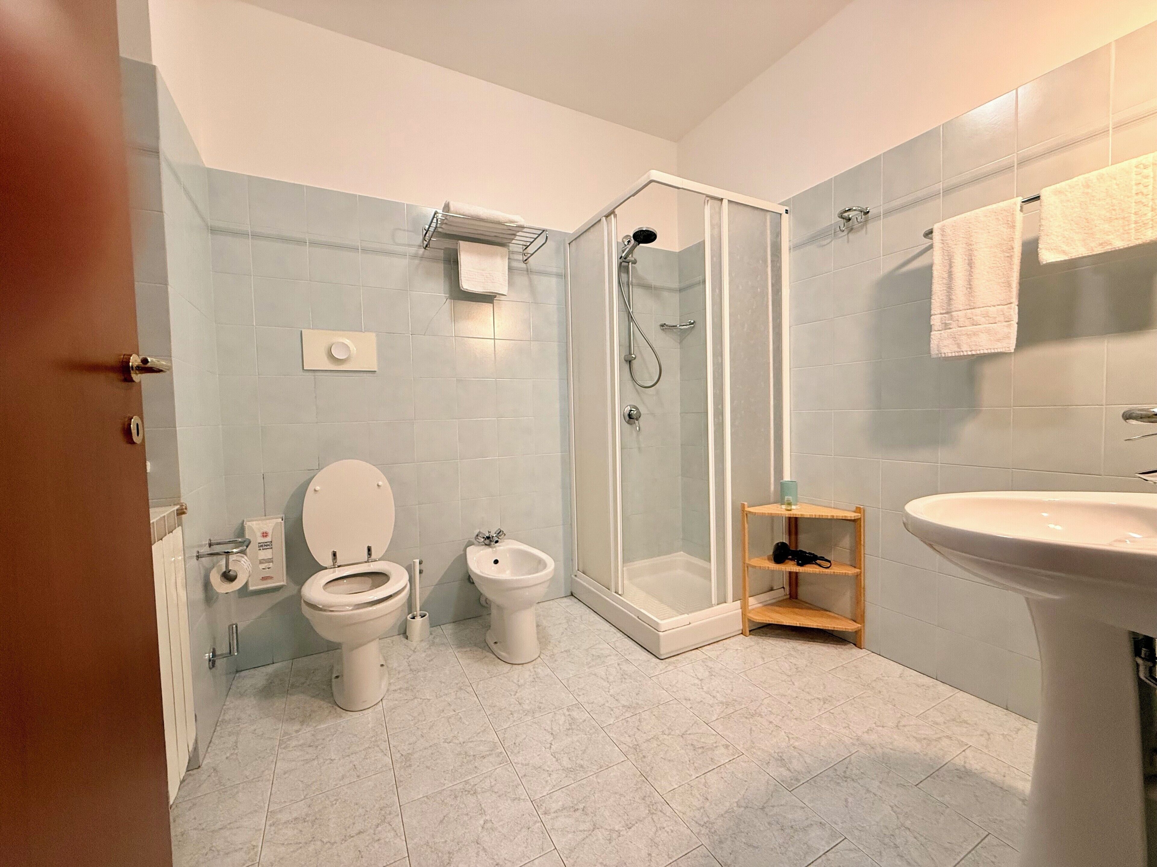 Un baño con inodoro, bidé, ducha y lavamanos.