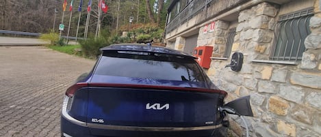 Un Kia EV6 azul estacionado frente a un edificio de piedra con balcón.