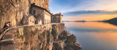 A historic building perched on a cliffside overlooking a calm lake.