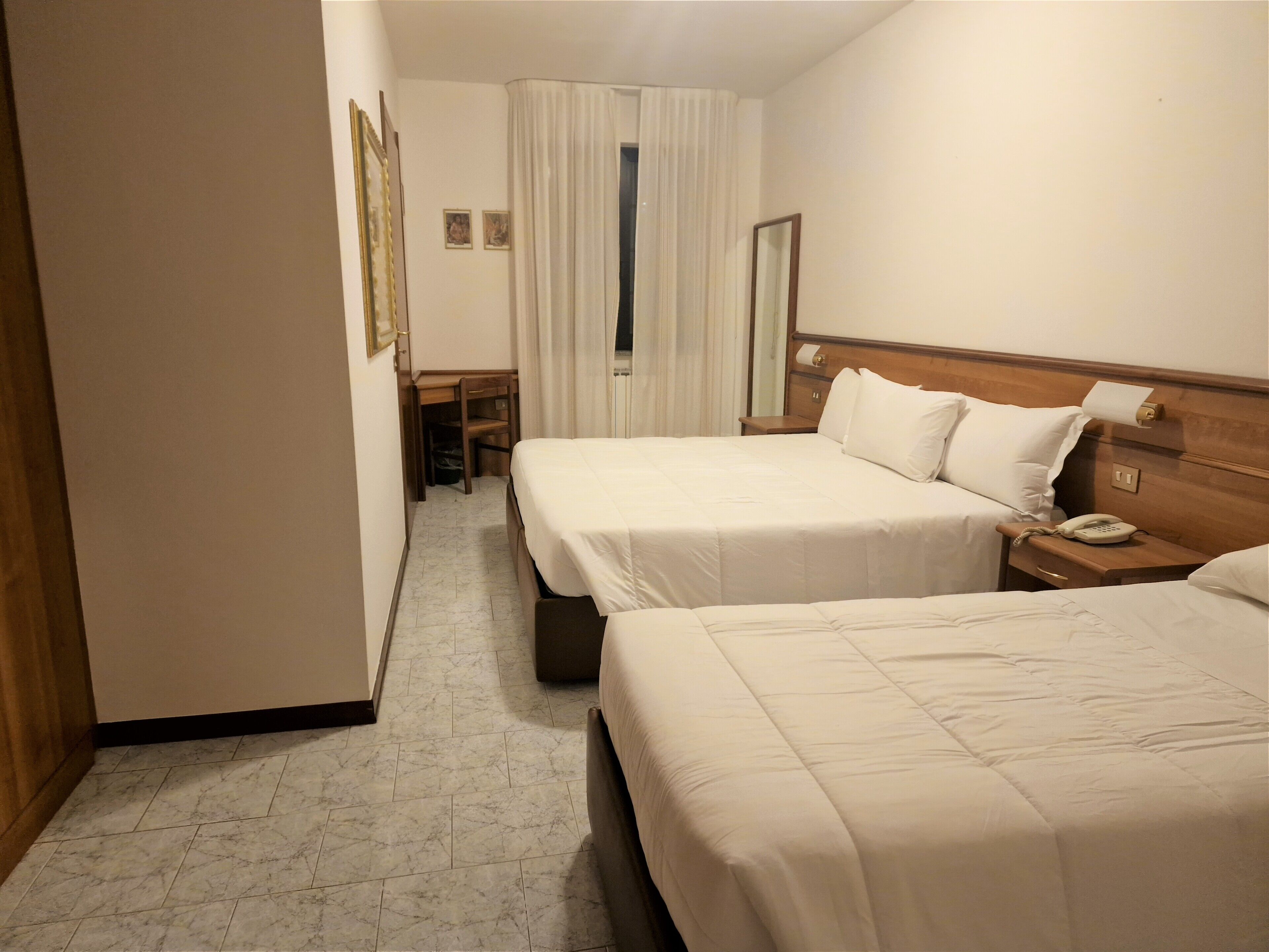 Habitación de hotel con dos camas, un escritorio, una silla y un baño.