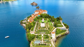 An island with a large building surrounded by gardens and a small island in the lake.