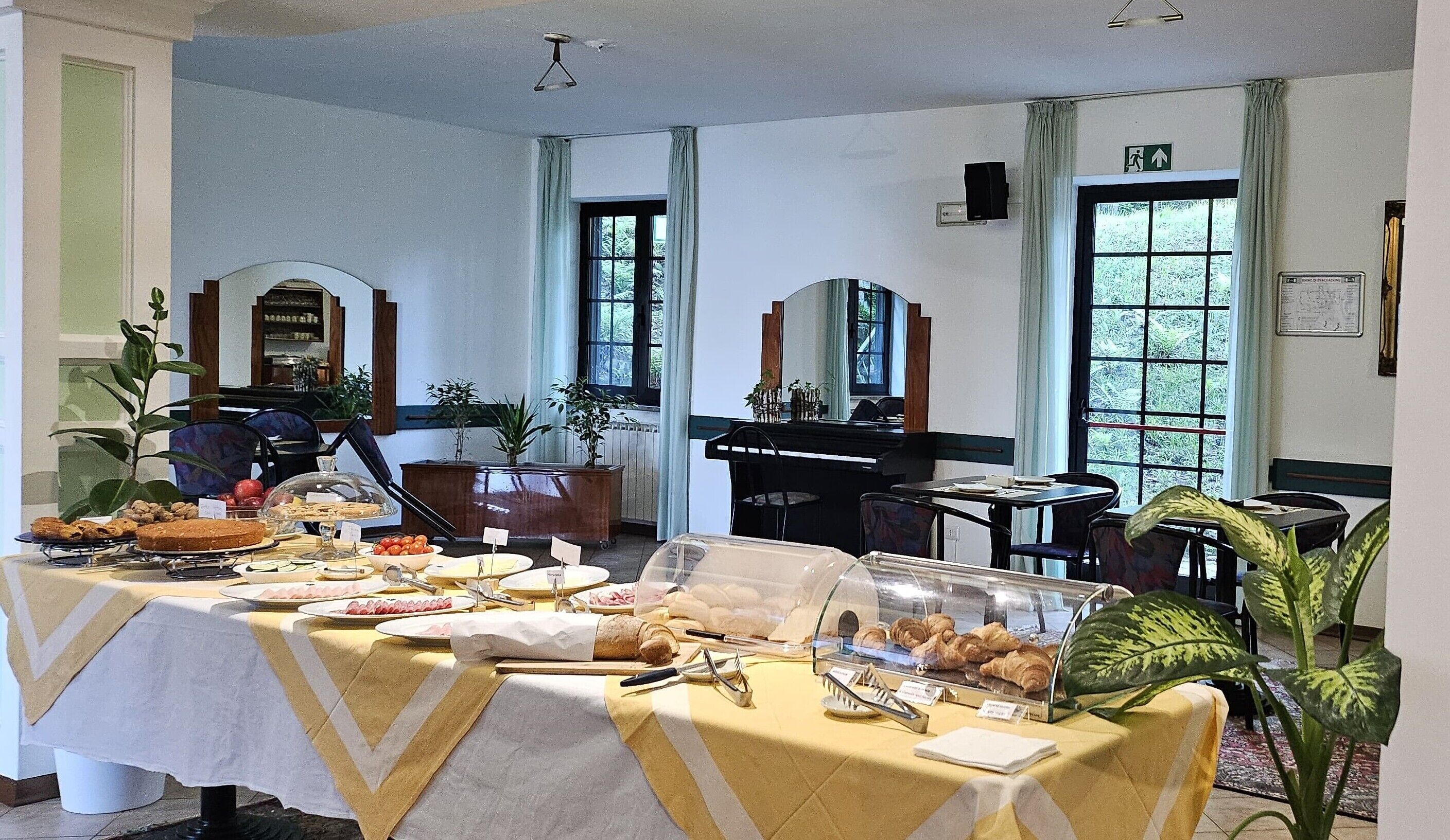 Spiseområde med et buffetbord, stole og et klaver i baggrunden.