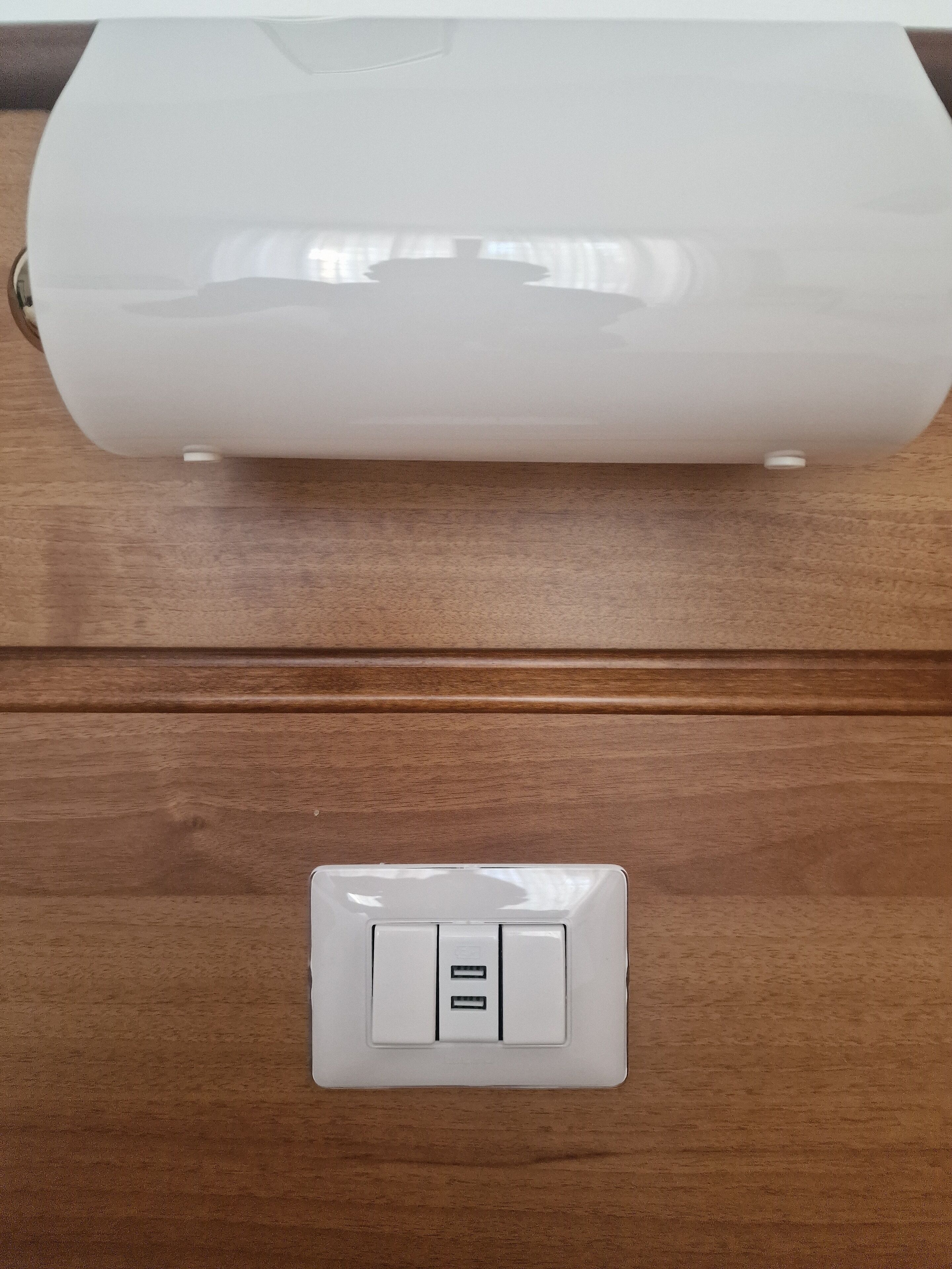 A white, cylindrical device on a wooden surface, with a white switch below it.