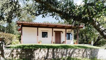 Une maison de plain-pied avec un toit en tuiles, une porte d’entrée et une petite fenêtre.