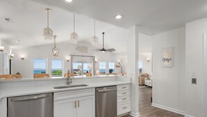 A modern kitchen with a large island, stainless steel appliances, and pendant lighting.