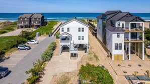 A beachfront property with multiple houses, a parking area, and a view of the ocean.