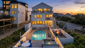 A two-story house with a swimming pool, outdoor seating, and a hot tub.