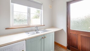 A kitchen with a window, sink, and wooden cabinets. - Summercove 04 - Family Estate (Lahinch)