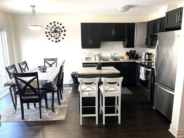 Enjoy meals in the kitchen and dining area, featuring a central island, table, chairs, and rug.