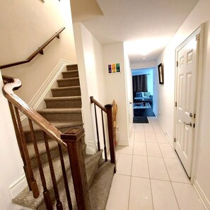 Staircase leads to a spacious hallway with a door and a glimpse of a living area.