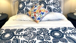 A bed with a white headboard, patterned bedding, and a colorful floral pillow. - Niagara Sleeps 6 Cozy 3bed 3bath Near Falls (Thorold)