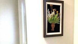 A bathroom with a white sink, a mirror, a framed picture of flowers, and a small potted plant on the toilet. - Niagara Sleeps 6 Cozy 3bed 3bath Near Falls (Thorold)