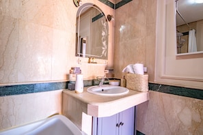A bathroom with a marble sink, a mirror, and a bathtub. - Magnificent Apartment (Marrakech)