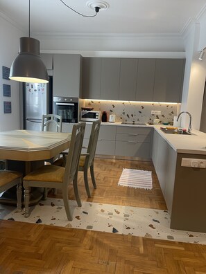 Une cuisine moderne avec des meubles gris, une table à manger en bois et un parquet à motifs en chevrons.