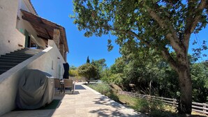 A covered outdoor seating area with a table and chairs, a covered table, and a staircase leading to a building. - 8-person villa in quiet location near lake and beach (Saint-Paul-en-Forêt)