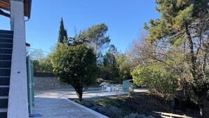 A paved pathway leading to a building entrance, surrounded by trees and a stone wall. - 8-person villa in quiet location near lake and beach (Saint-Paul-en-Forêt)