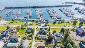An aerial view of a marina with boats docked, surrounded by residential houses and a well-maintained lawn.