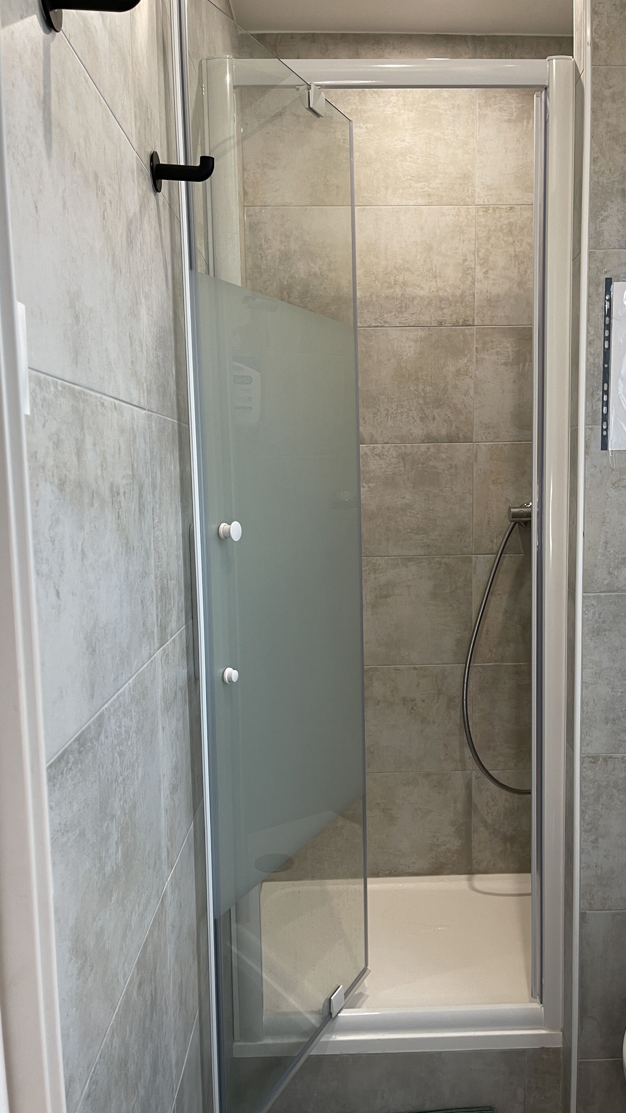 A glass-enclosed shower stall with a showerhead and a towel rack.