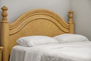 Uma cama de madeira com cabeceira curva e duas almofadas.