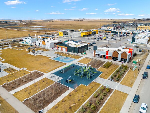 Vista aérea de uma área comercial com um restaurante McDonald's, um posto de gasolina e um estacionamento.