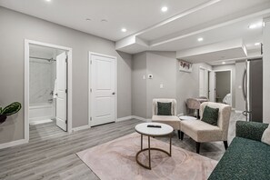 Uma sala de estar moderna com cores neutras, uma mesa de centro redonda e um espaço de estar com sofá e poltronas.