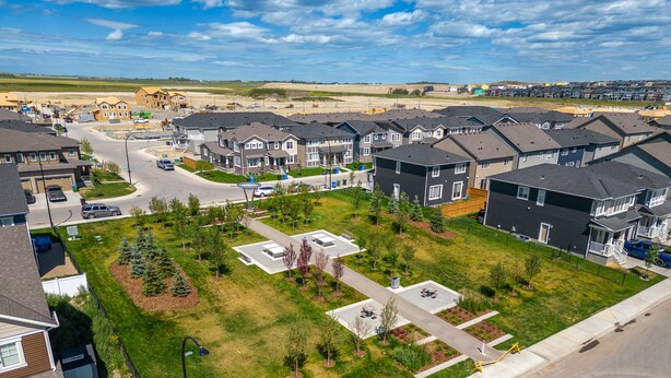 Un barrio residencial con casas modernas, un espacio verde central y una calle principal.