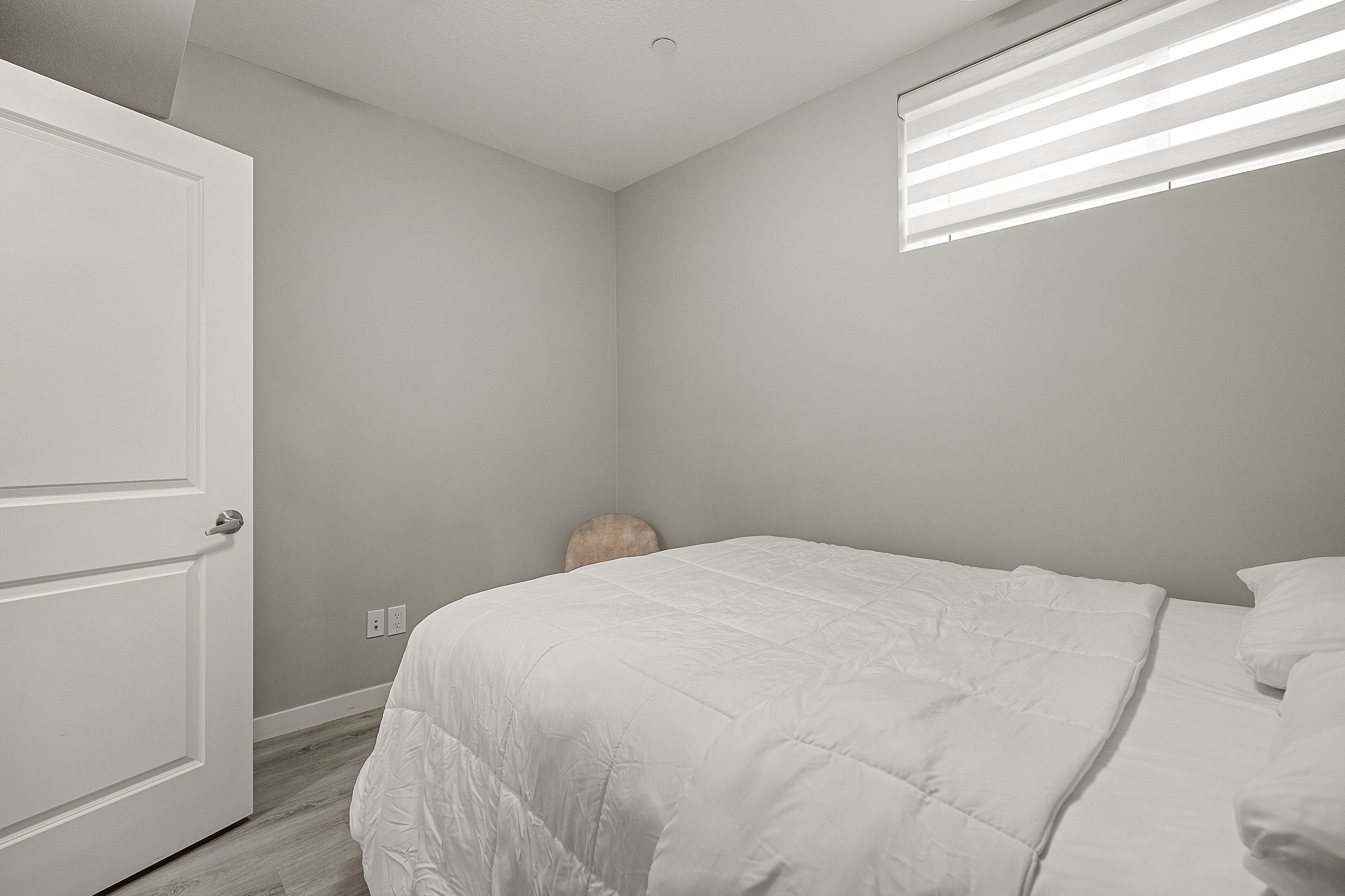 Une chambre à coucher avec un lit, une porte et un luminaire au plafond.