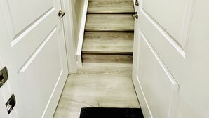 Una escalera con paredes blancas y piso de madera que conduce a una plataforma.