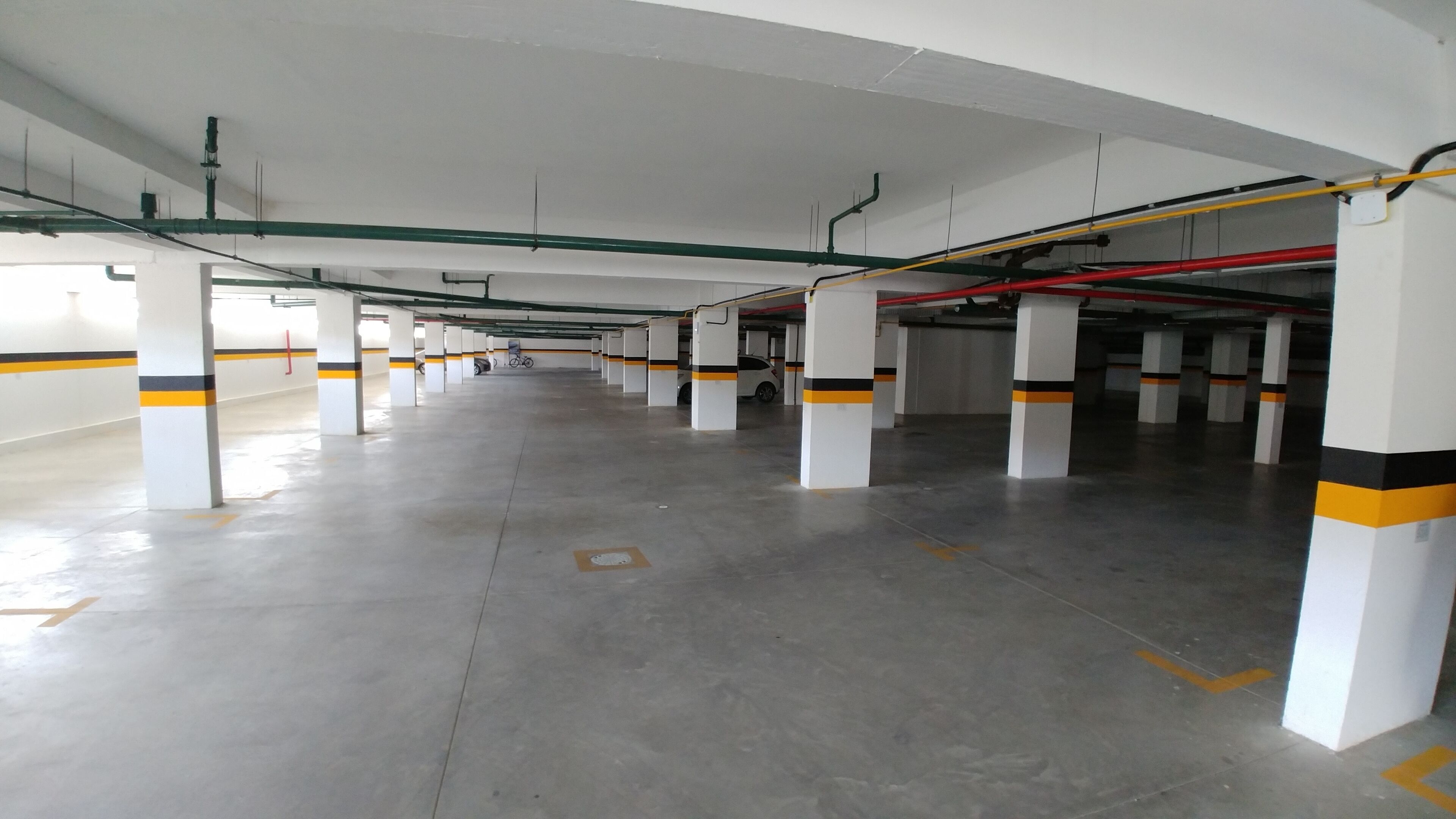A multi-level parking garage with white pillars and yellow stripes, featuring a clean, organized layout.