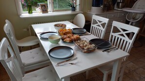 A dining table set with plates, bowls, and cutlery, surrounded by white chairs. - Forest Family Home (Ytterhogdal)