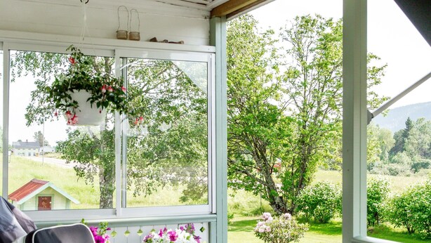 A covered porch with a table, chairs, and hanging flower baskets. - Forest Family Home (Ytterhogdal)