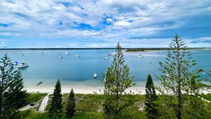 A coastal view with boats on the water, a sandy beach, and surrounding greenery. - Ocean View 2BR Apartment w/hot tub. Heated pool, Games room, Gym (Biggera Waters)