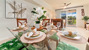 Un espace repas avec une table en verre, des chaises en bois et une vue sur l’extérieur.