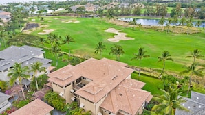 Un parcours de golf doté d’un club-house, de palmiers et d’un lac.