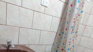 Ein Badezimmer mit einem braunen Waschbecken, einer Toilette und einem Duschvorhang mit bunten Punkten.