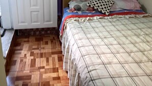 Ein Zimmer mit einem Bett, einer Tür mit der Aufschrift 'Cierre Despacio' und einem Holzbodenparkett.