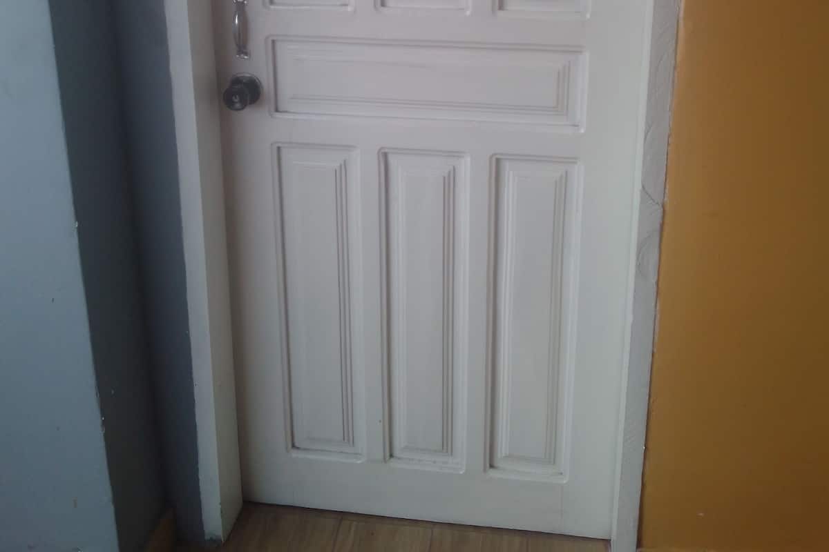 Une porte blanche avec une pancarte indiquant « Fermer doucement » et une poignée de porte.