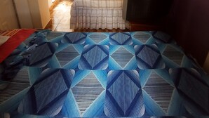 Ein Schlafzimmer mit einem Bett, einem Fernseher und einer Tür zu einem weiteren Raum.