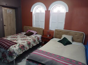 A bedroom with two single beds, a wooden door, and two arched windows. - Hotel Tanta Wasi (Quito)