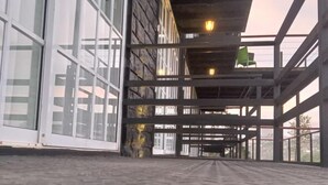 Un bâtiment doté de grandes fenêtres en verre, d’une façade en pierre et d’une structure métallique.