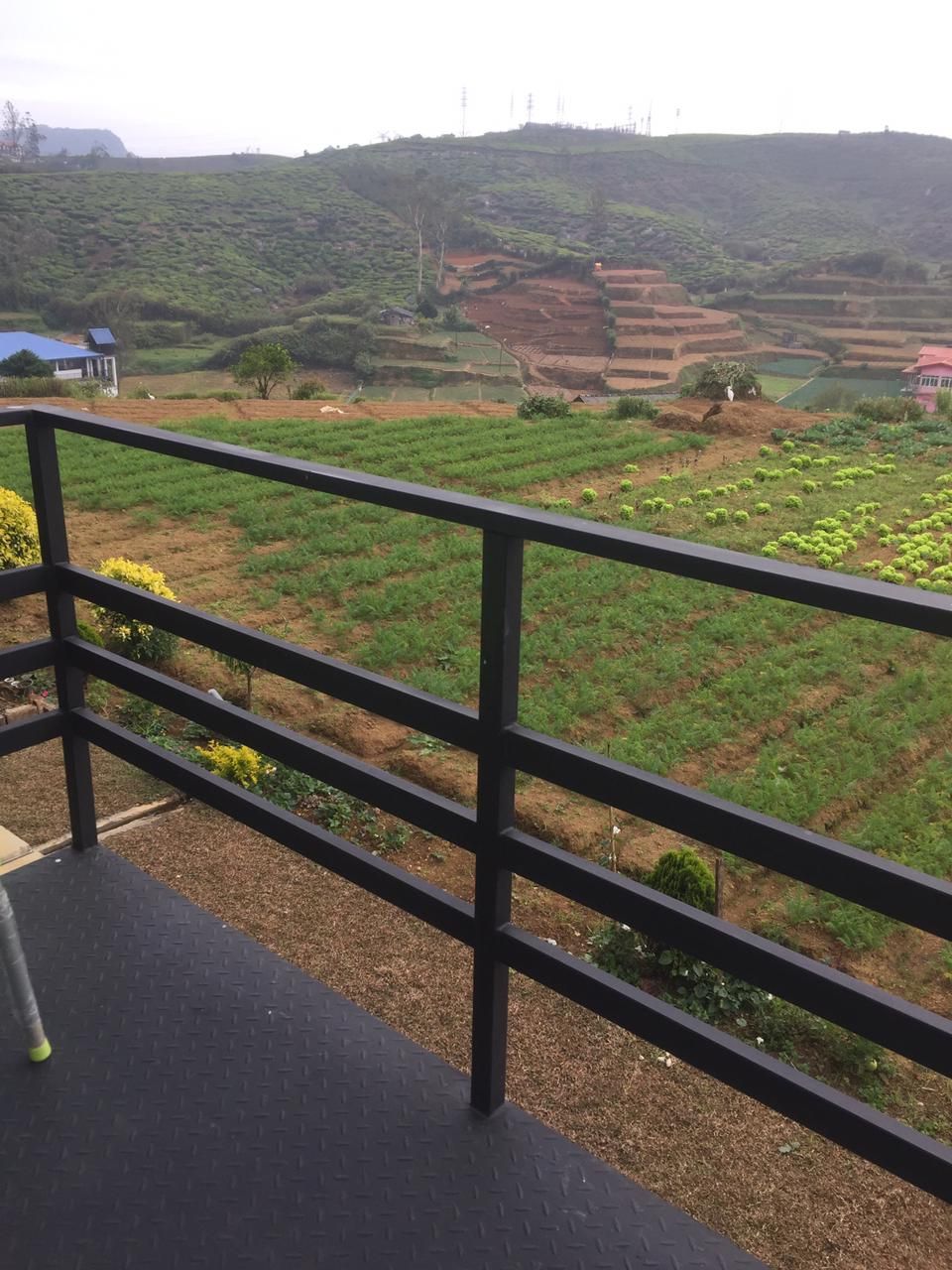 Une terrasse dotée d’une rambarde en métal, d’où l’on peut admirer des champs en terrasses et une colline lointaine.