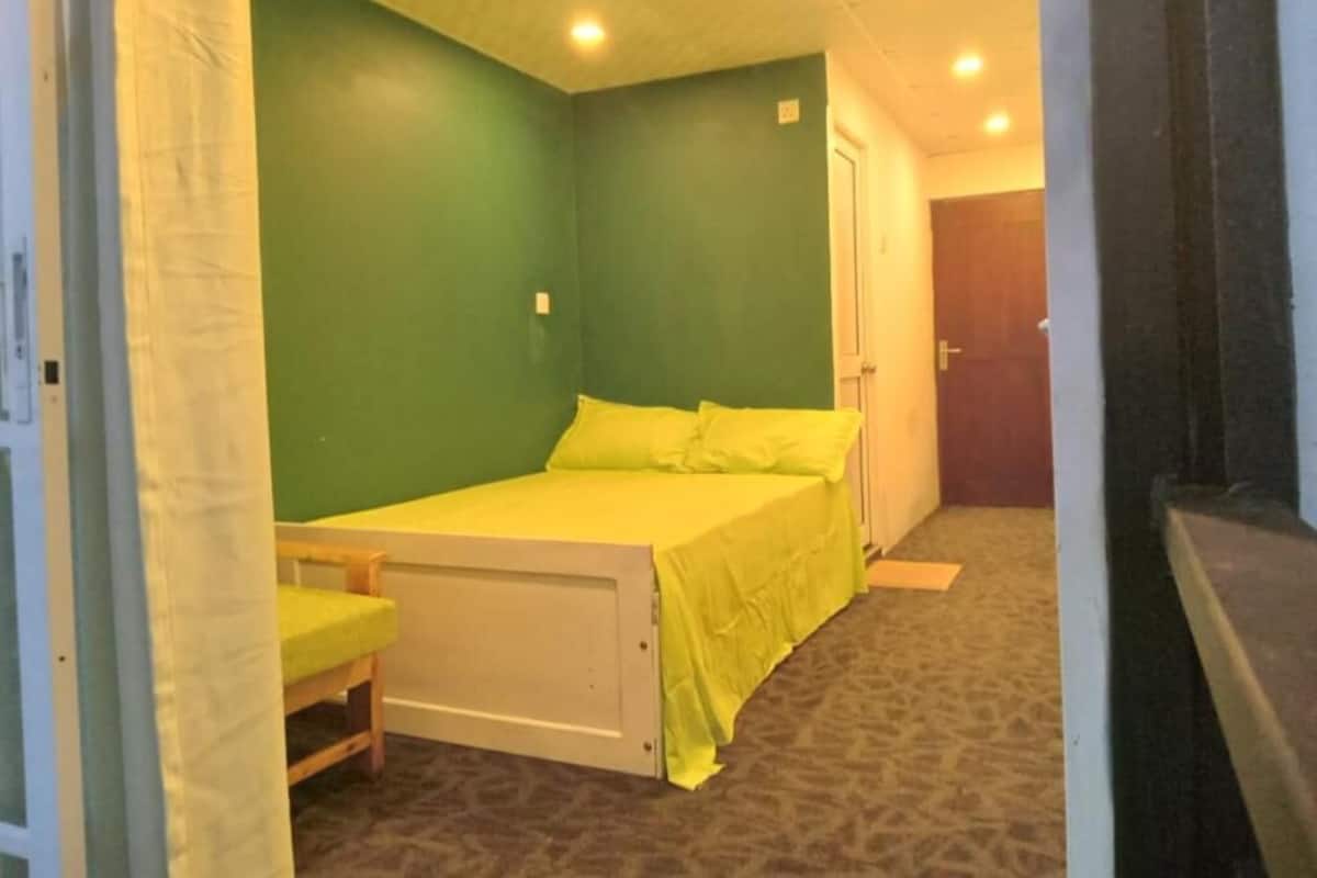 A room with a bed, a chair, and a door.