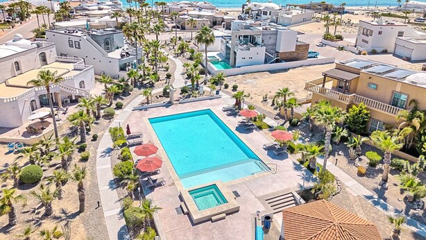 A resort with a large swimming pool surrounded by palm trees and sun loungers. - Modern Luxury Beachside Retreat (Puerto Peñasco)